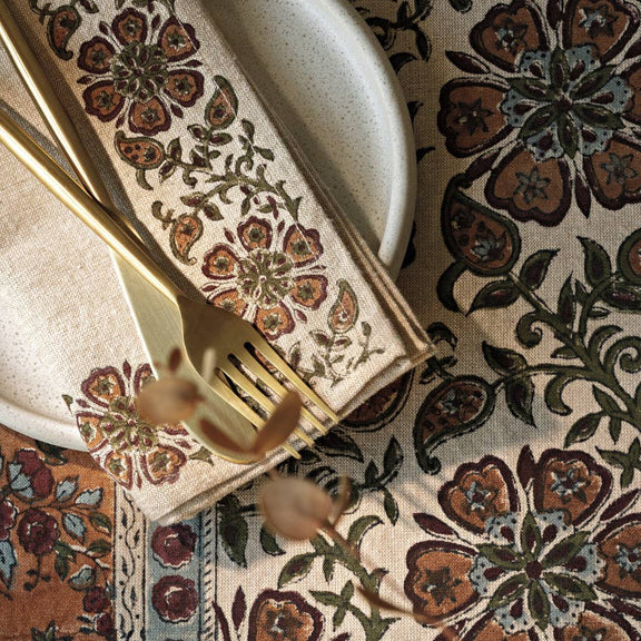Decorative table setting with floral patterned placemat, napkin, and cutlery.