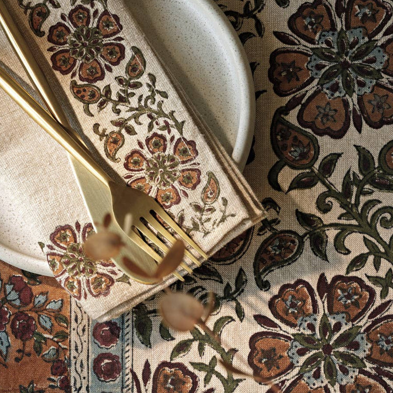 Decorative table setting with floral patterned placemat, napkin, and cutlery.