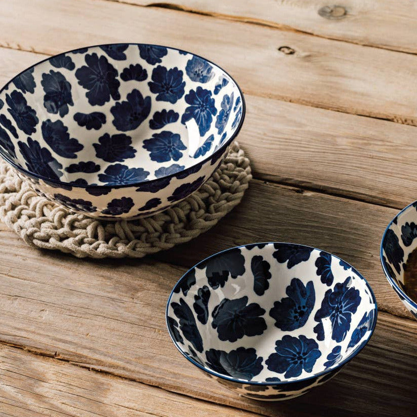 Three ceramic bowls with blue floral patterns on a wooden surface, one containing soup.